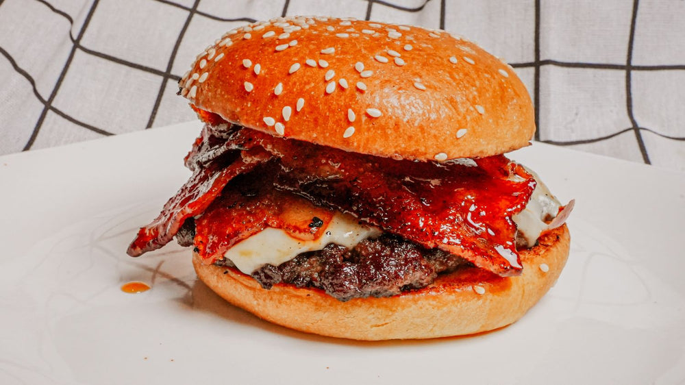 Hamburger with sesame seed bun on a white surface with a grid pattern