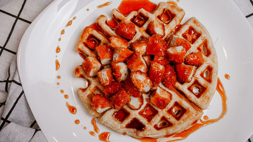 Waffle with chicken and sauce on a white plate