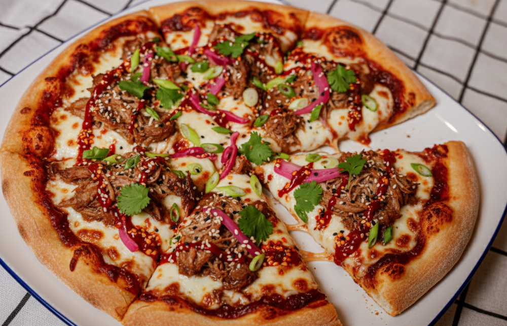 Pizza with beef and green onions on a white plate with a blue rim, on a tiled floor.