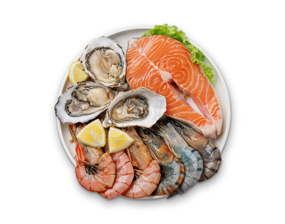Seafood platter with salmon fillet, oysters, shrimp, and lemon slices on a white plate