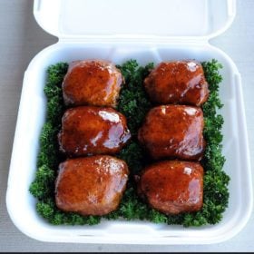 Christie Vanover chicken thighs in a container on a bed of lettuce