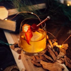 Girl Carnivore Smoky Old Fashioned cocktail in glass with smoked cherry