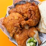 a plate of nashville hot fried chicken with pickles and white bread