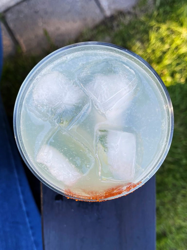 a glass of texas ranch water sitting on the arm of a chair with grass in the background