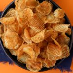 a bowl of waffle chips on an orange background