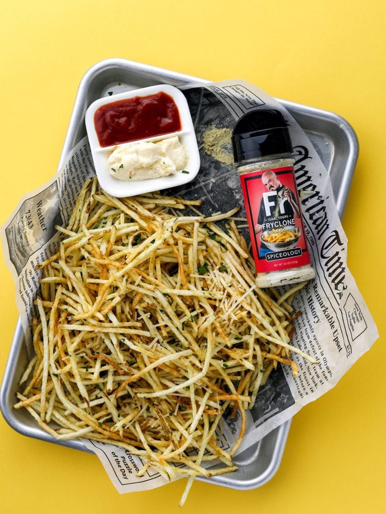 a sheet pan of shoestring french fries on a yellow background