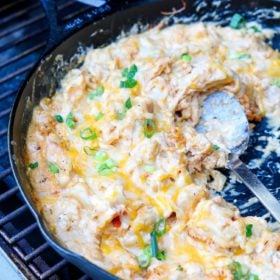 a skillet with mac & cheese on a grill