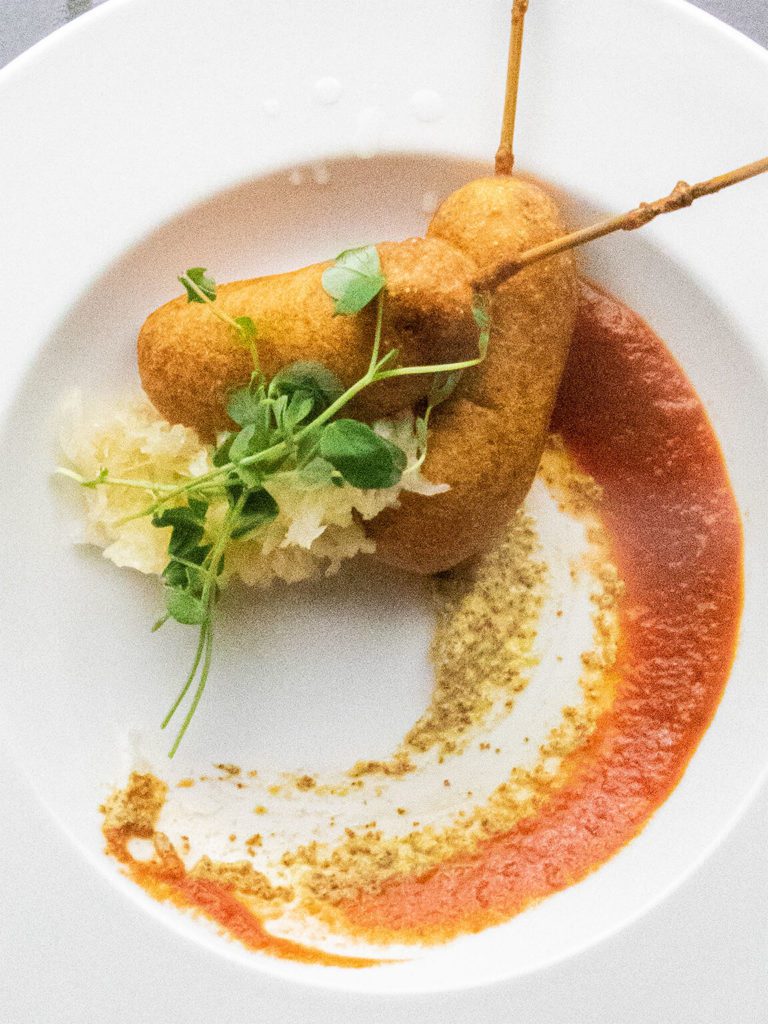 Bratwurst corn dogs on a plate with tomato jam