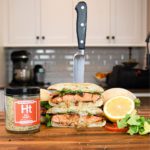 Hot Honey Salmon Sandwich on cutting board with knife through it