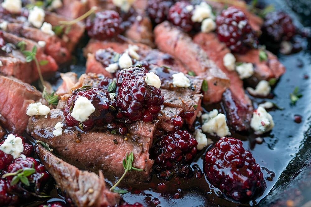 NY strip steak sliced with boozy blackberries and bleu cheese in cast iron