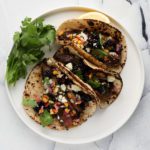 flat iron steak tacos with blackberry salsa on a white background