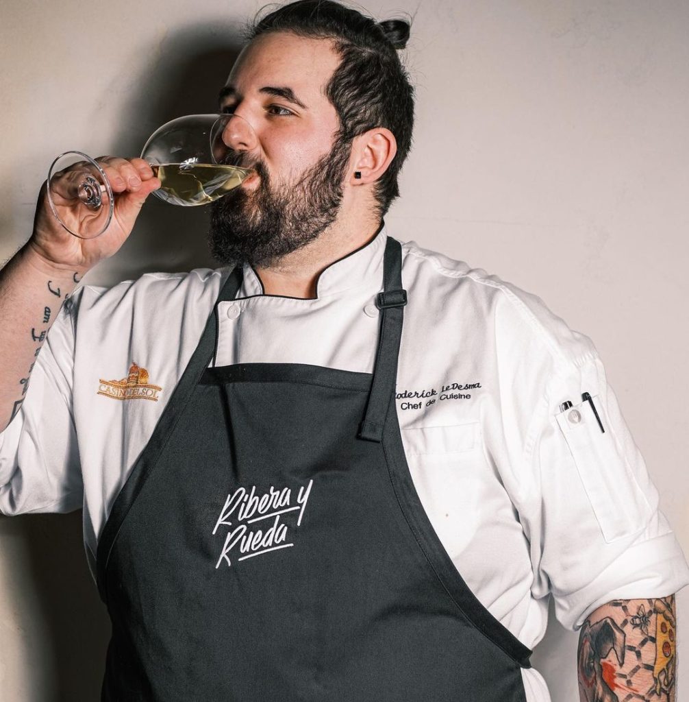 Roderick LeDesma in chef coat and apron drinking wine