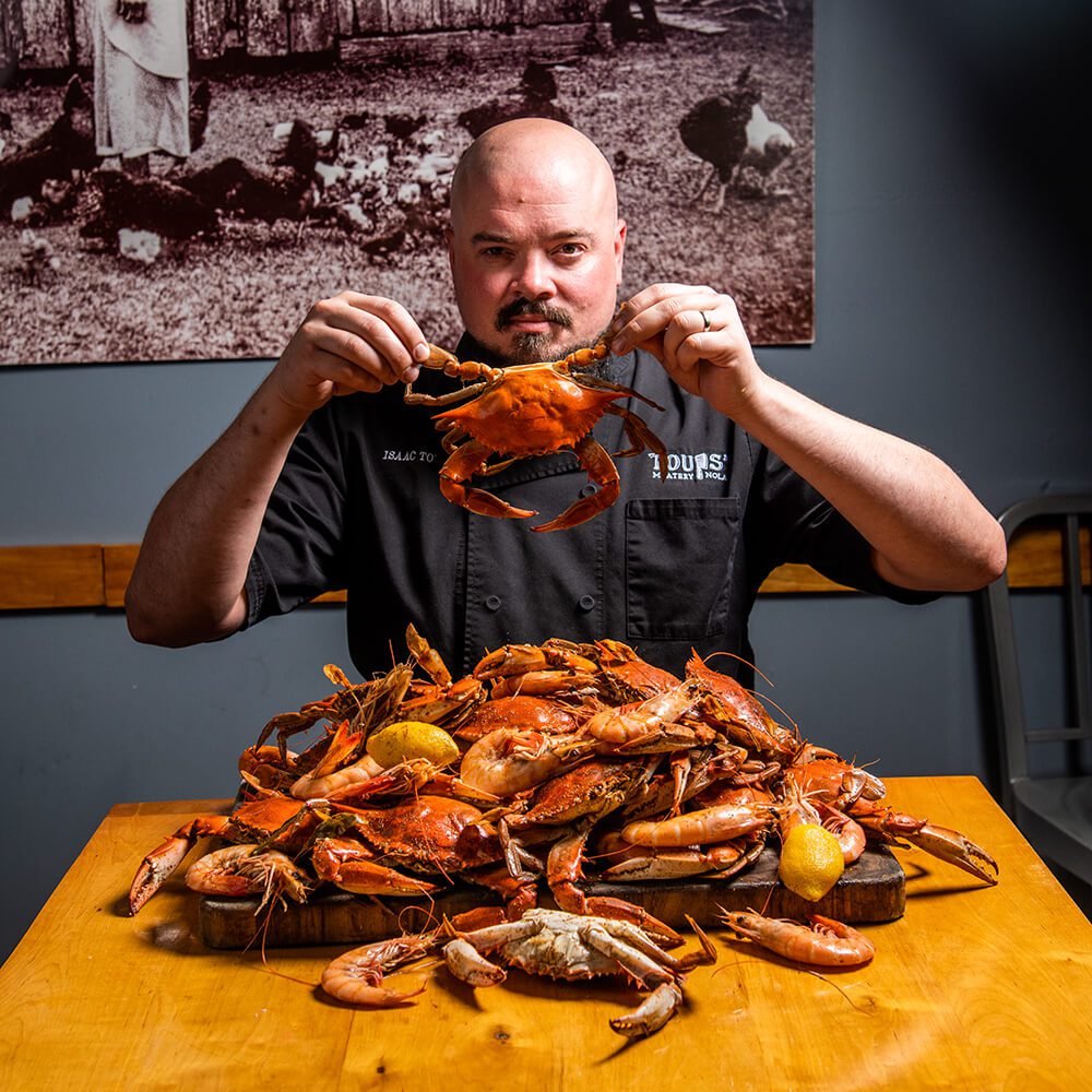 Chef Isaac Toups holding grab with pile of seafood