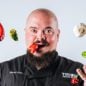 Chef Isaac Toups headshot holding pepper in mouth