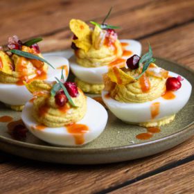 Bob Marley One Love Deviled Eggs on plate with pomegranate chili sauce