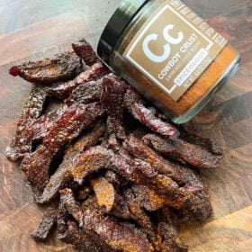 cowboy crust beef jerky pieces on cutting board with spice jar
